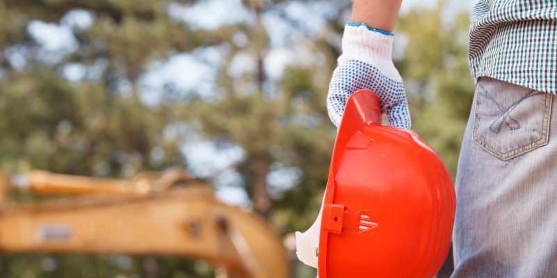 closeup of engineer holding orange helmet on construction site outdoors